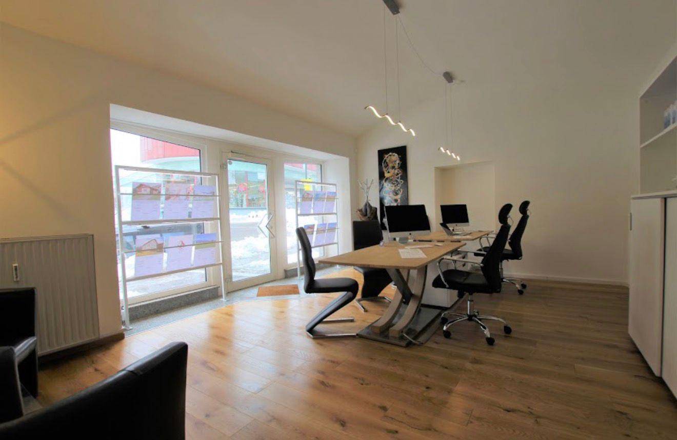 Geräumiges Büro mit viel Tageslicht, Holzboden und modernen Arbeitsplätzen.