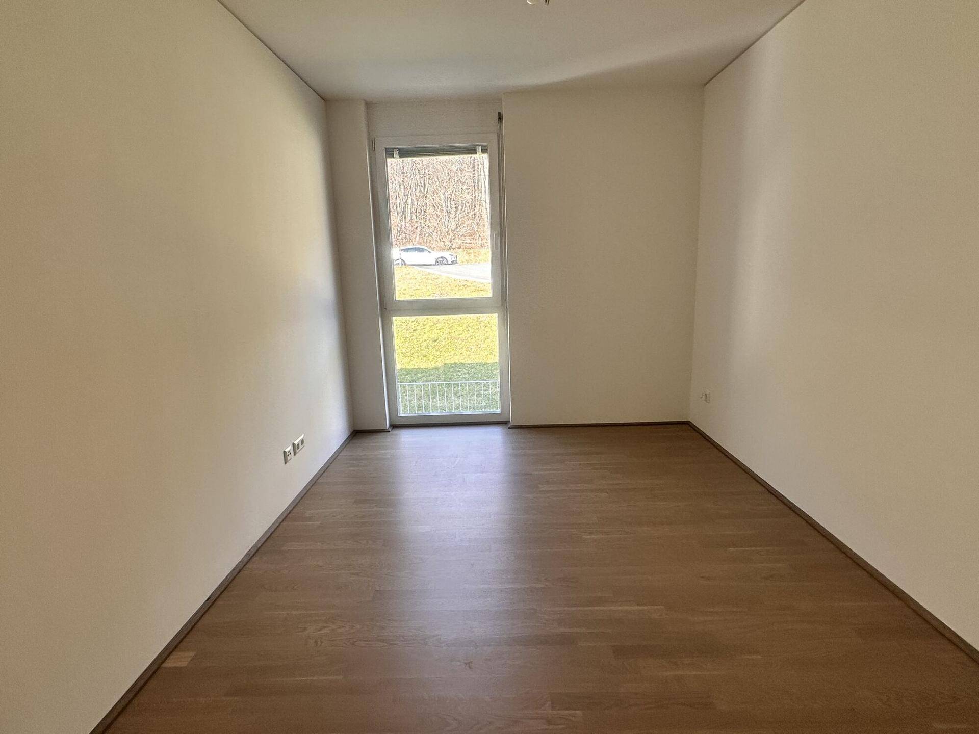 Geräumiges Schlafzimmer mit Holzboden und großem Fenster zur Natur.