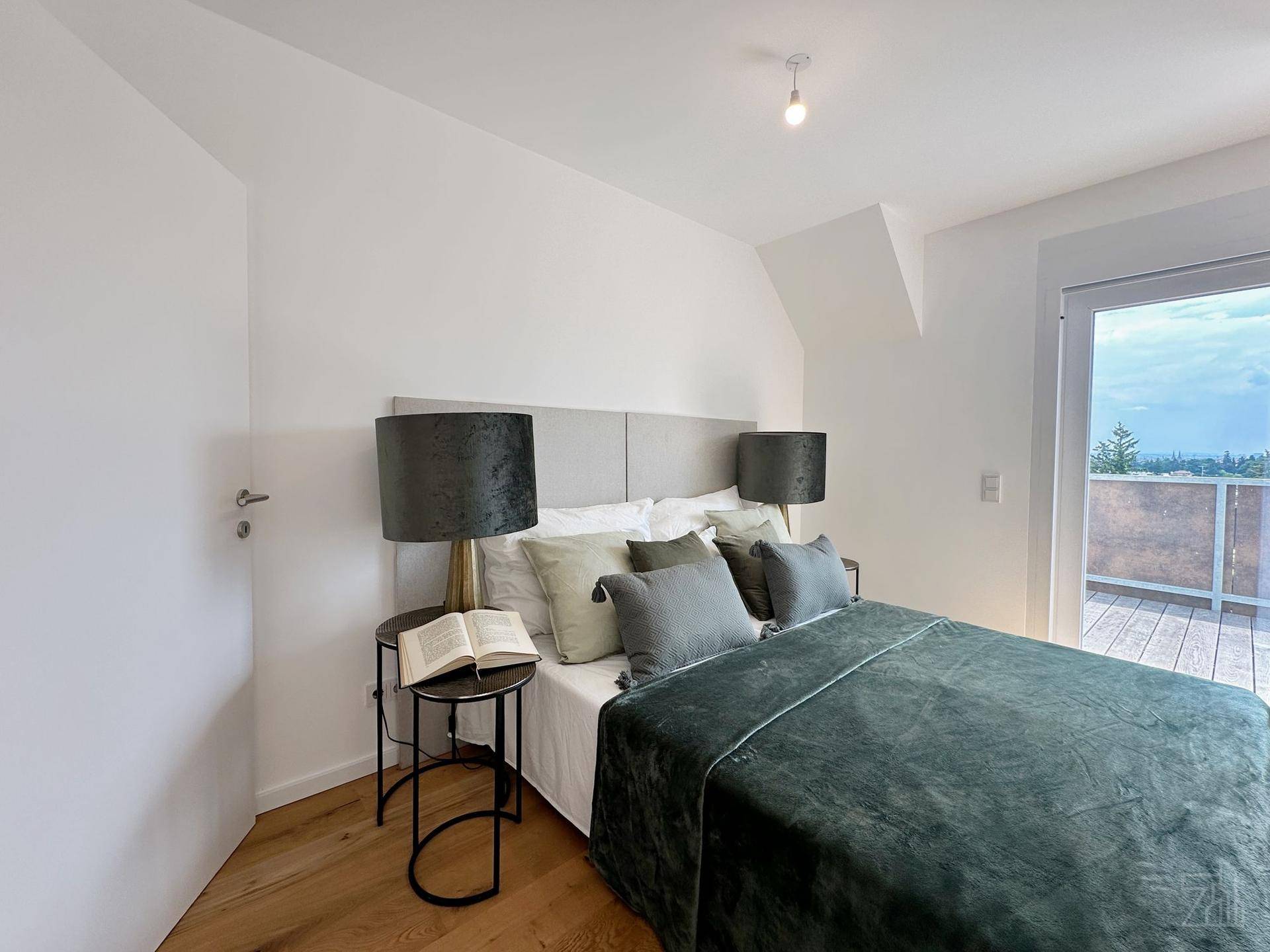 Gemütliches Schlafzimmer mit Holzboden, Balkonzugang und moderner Einrichtung im Dachgeschoss.