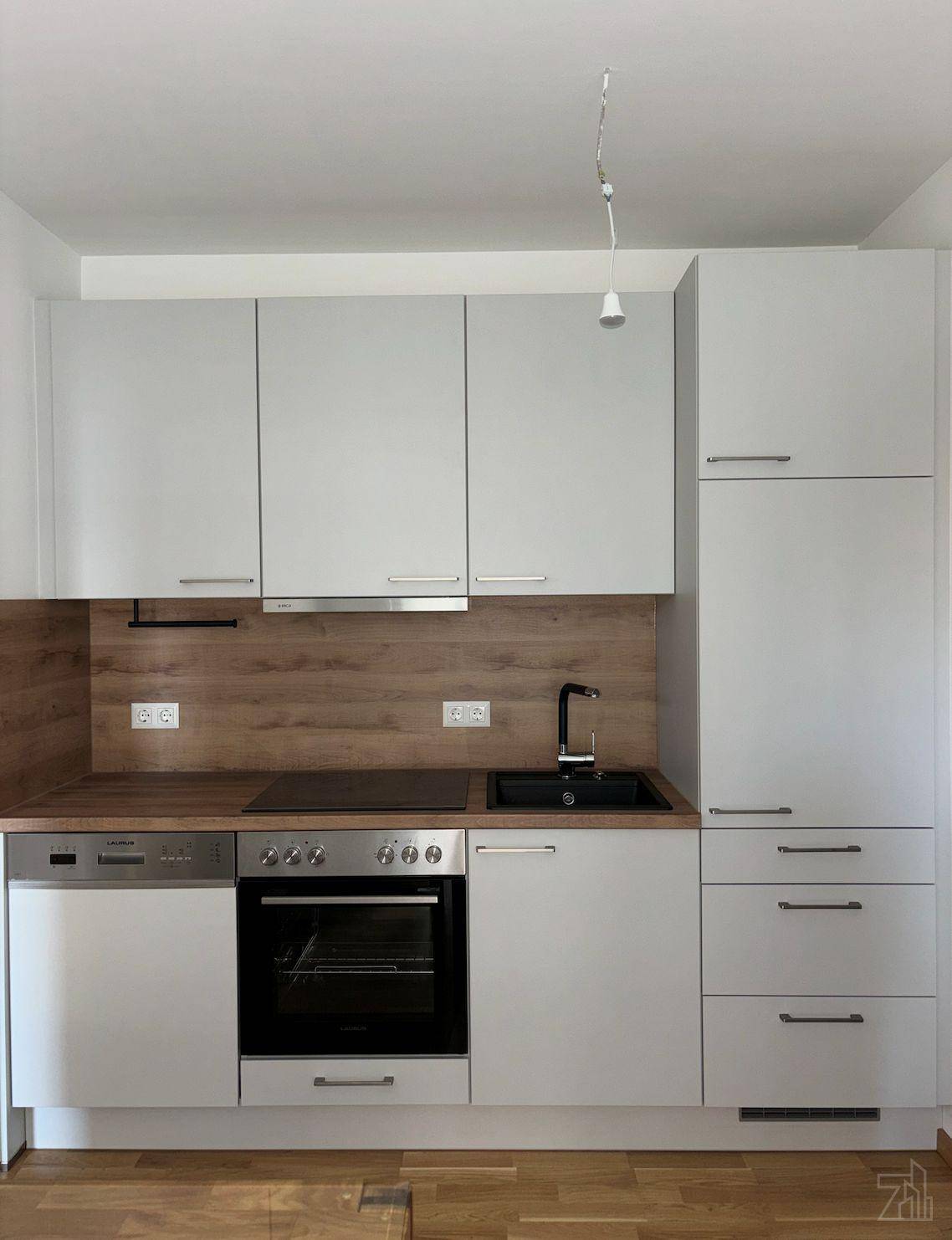 Moderne weiße Einbauküche mit Holz-Arbeitsplatte und integrierten Elektrogeräten.