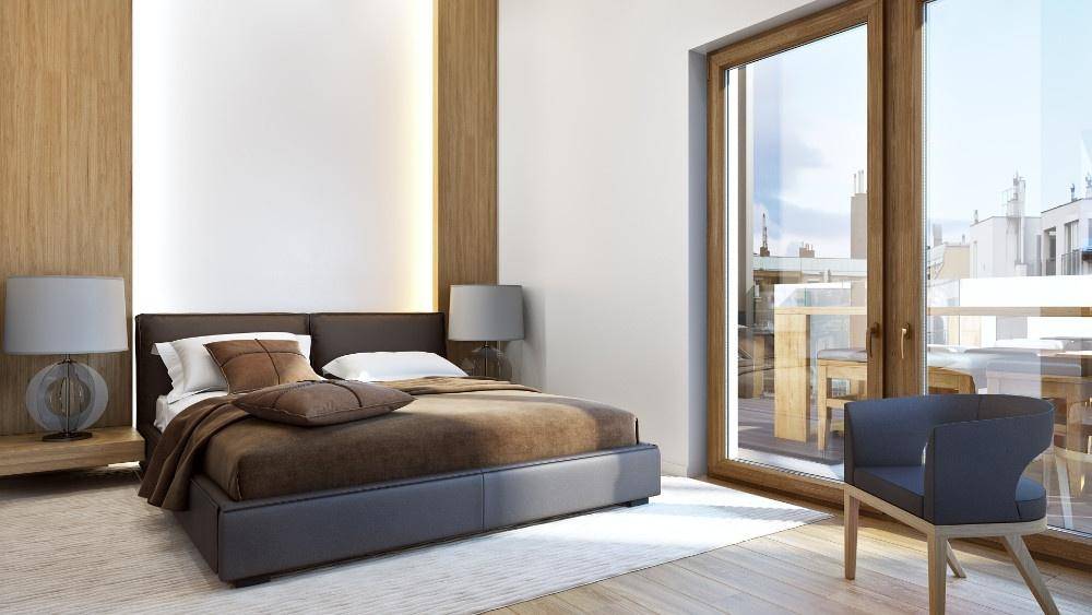 Schlafzimmer mit Holzboden, großem Bett und Zugang zu einem Balkon oder einer Terrasse.