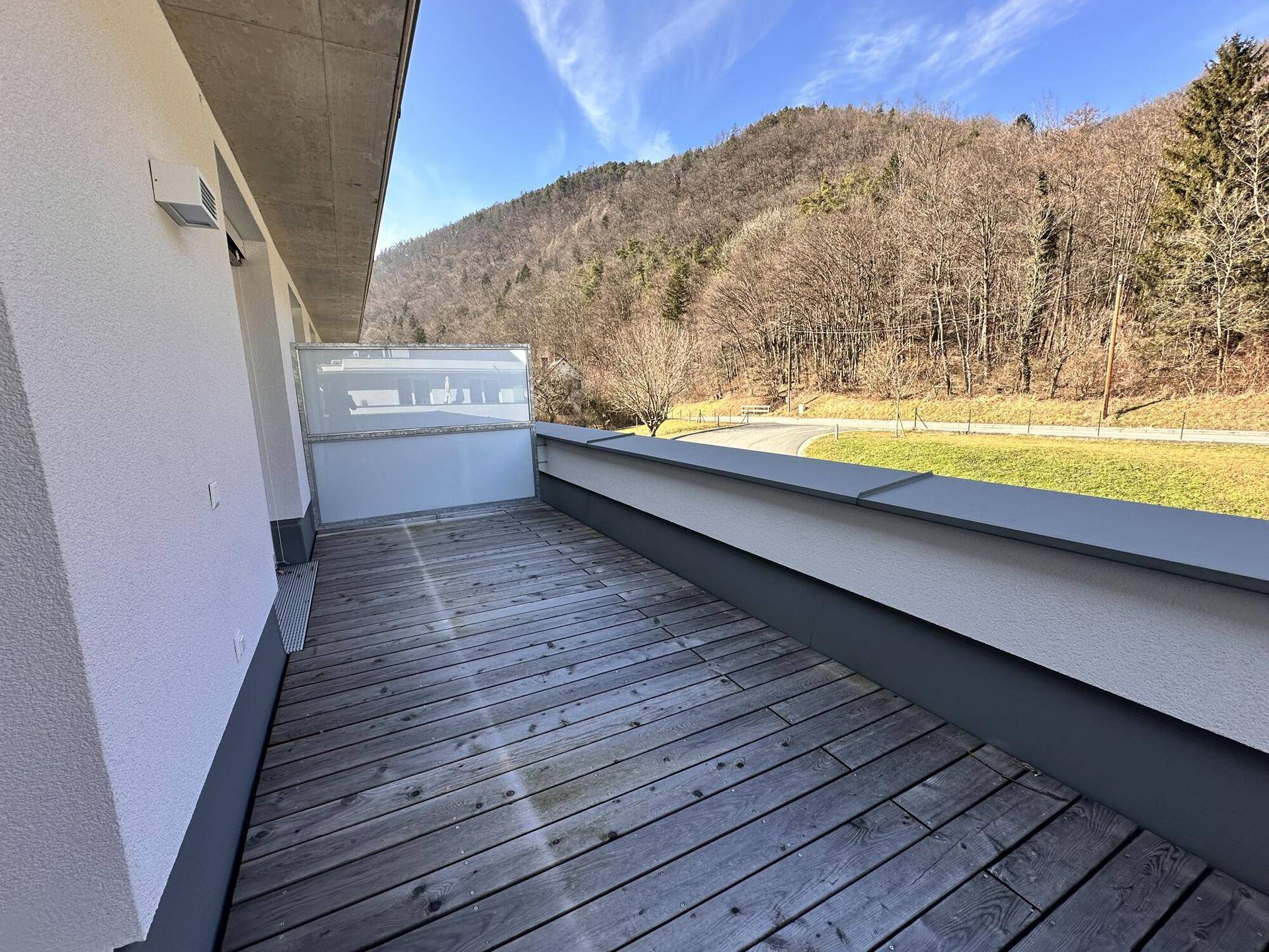 Geräumige Dachterrasse mit Holzboden und weitem Blick auf die bewaldeten Hügel.