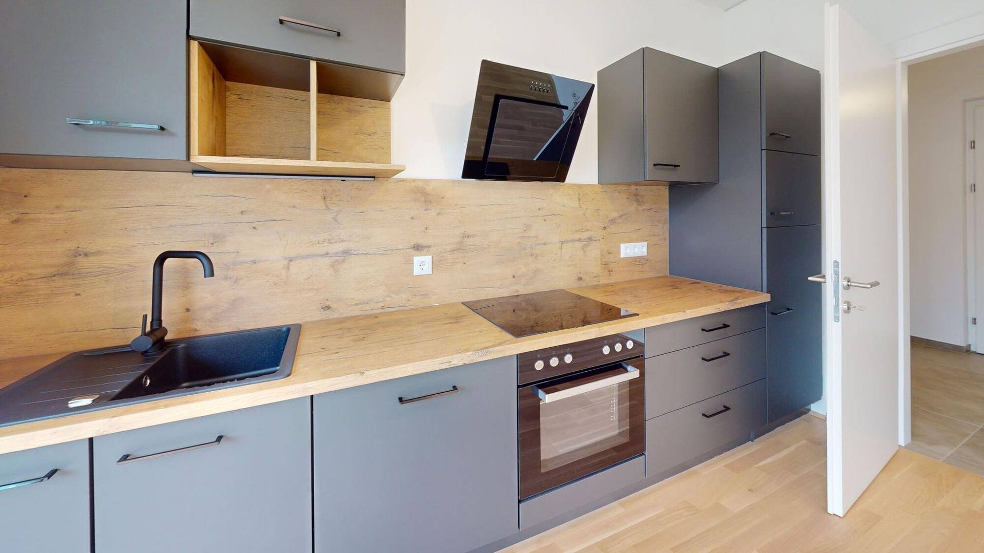 Moderne Einbauküche in Grau mit Holzoptik-Arbeitsplatten und hochwertigen integrierten Geräten.