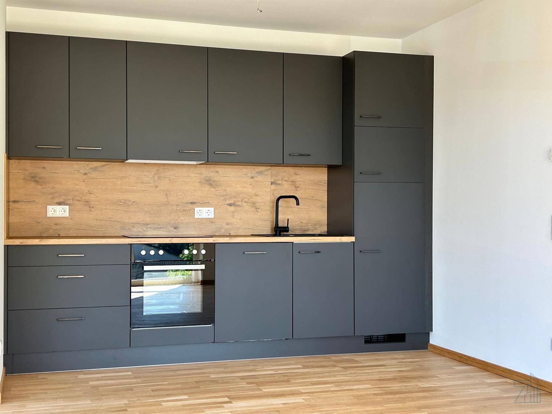 Moderne Einbauküche in Schwarz mit Holzdetails, integriertem Backofen und viel Stauraum.