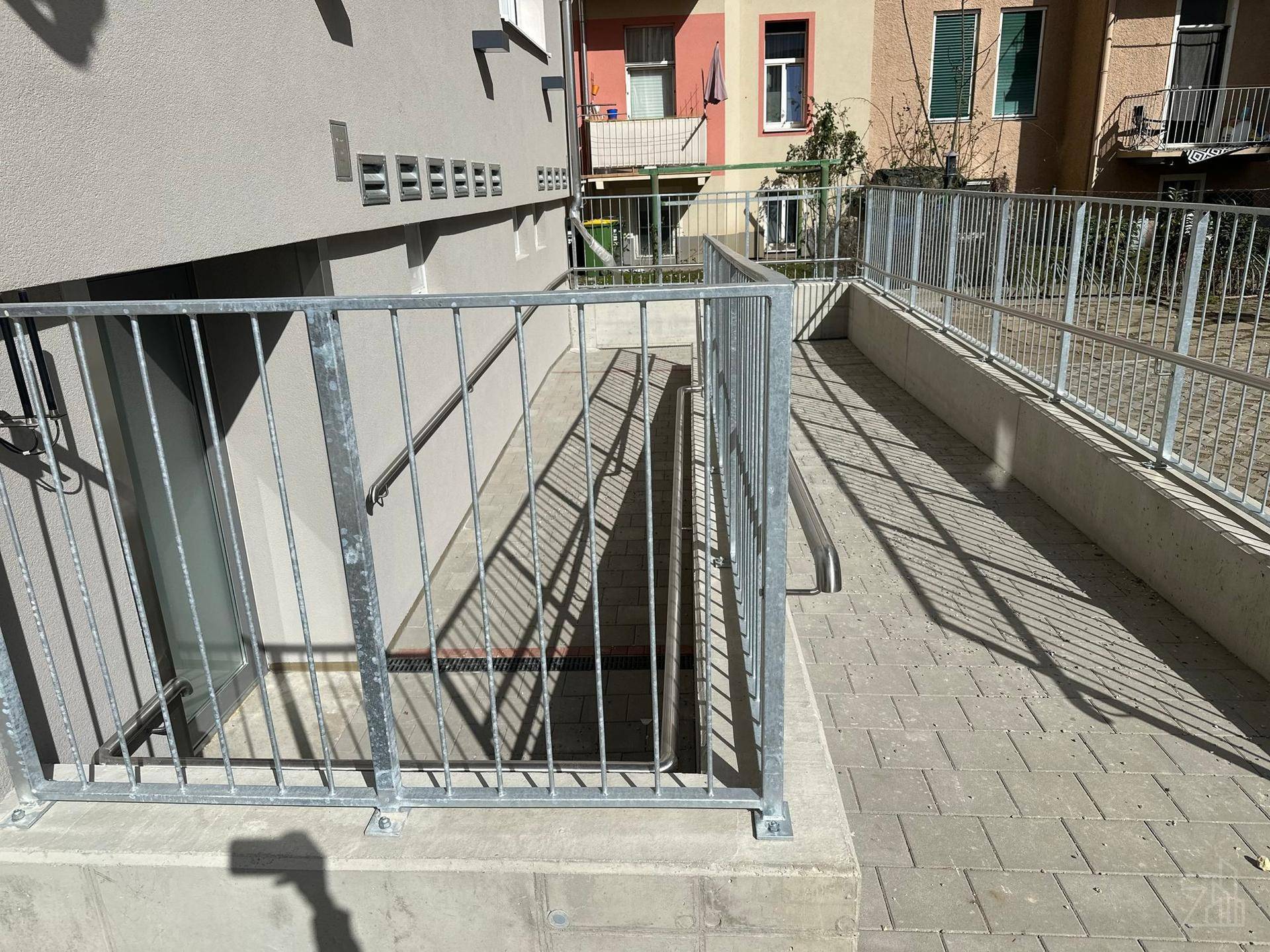 Barrierefreier Zugang mit Rampe und Treppe zum Untergeschoss eines Wohnhauses.