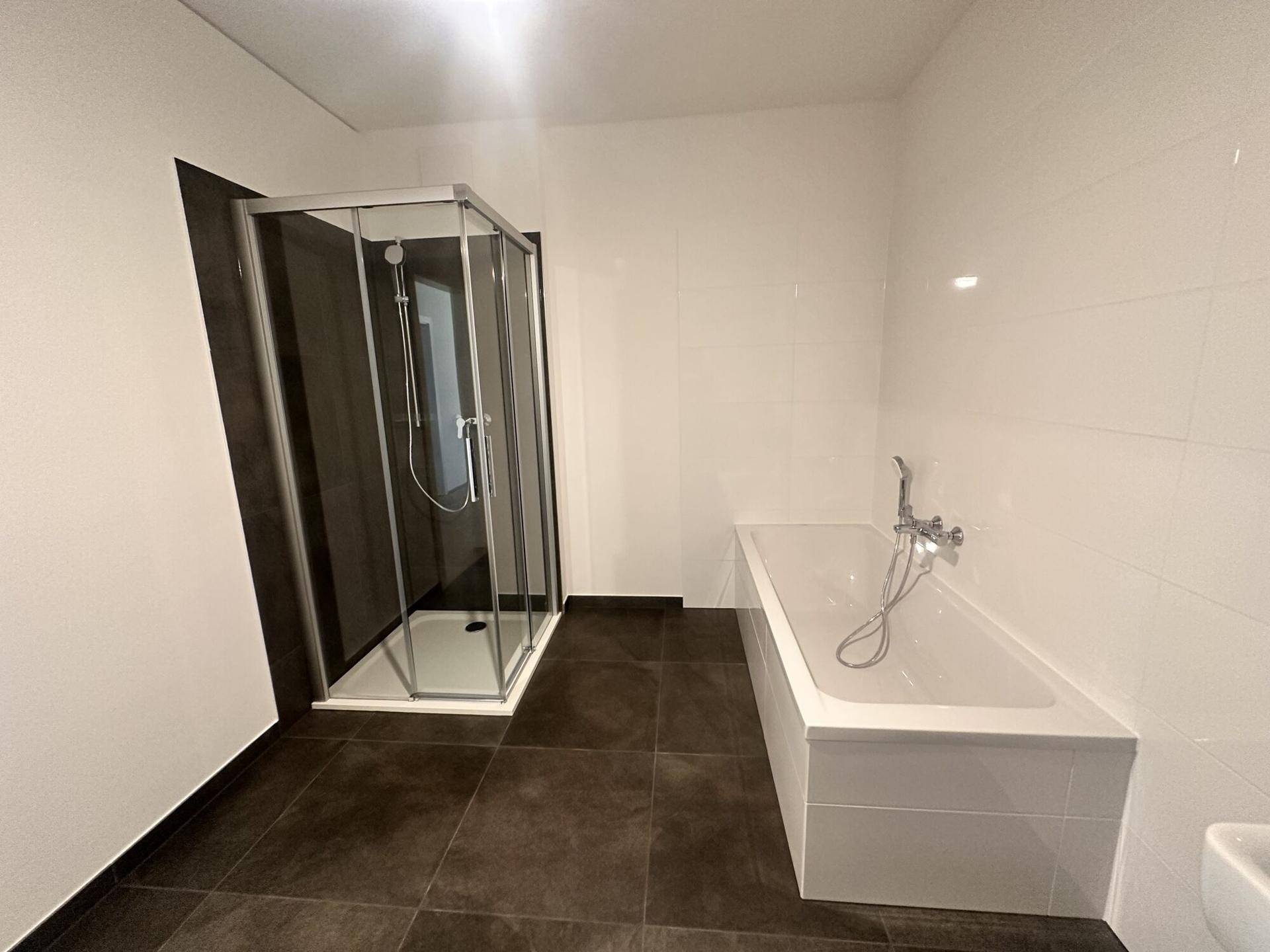 Helles Badezimmer mit Badewanne, Glasduschkabine und modernem Waschtisch.