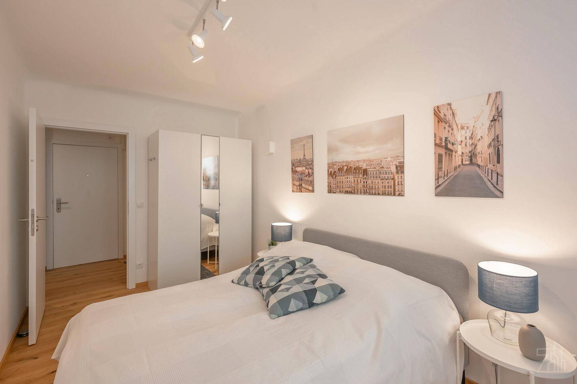Schlafzimmer mit Doppelbett, Spiegelschrank und Zugang zum Flur, hell und einladend gestaltet.