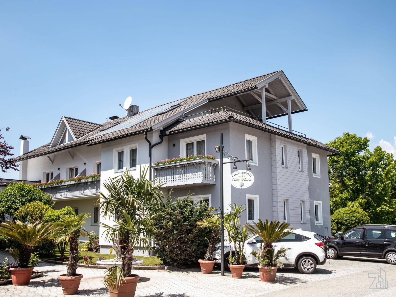 Ansicht des modernen Gebäudes mit Satteldach, Balkonen und Parkplätzen im Freien.