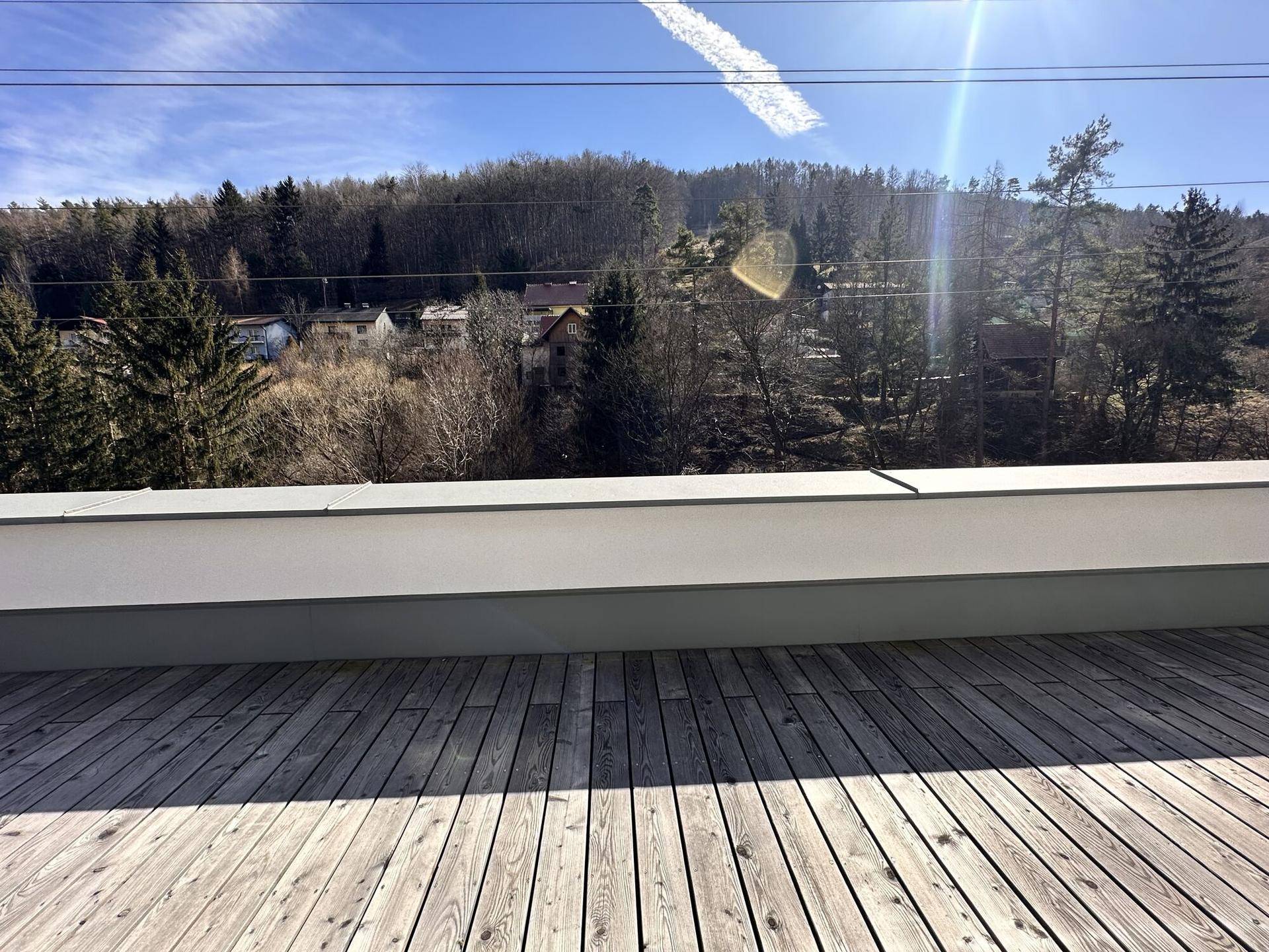 Geräumige Dachterrasse mit Holzboden und weitem Blick auf die umliegende grüne Landschaft.