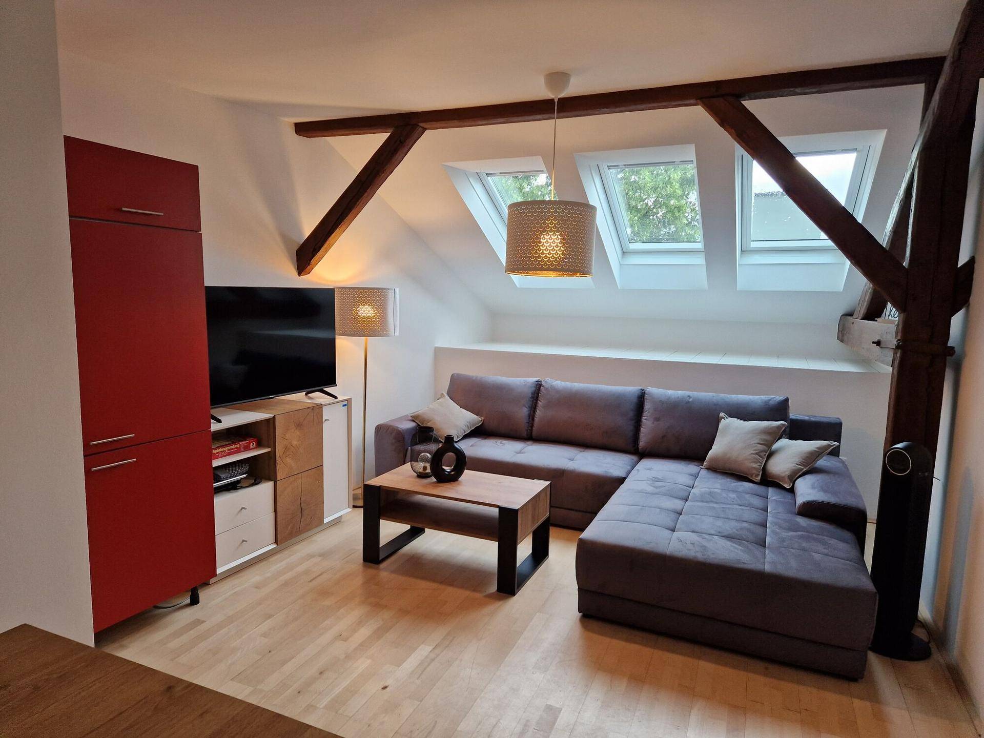 Gemütliches Wohnzimmer im Dachgeschoss mit Holzbalken und Dachfenstern.