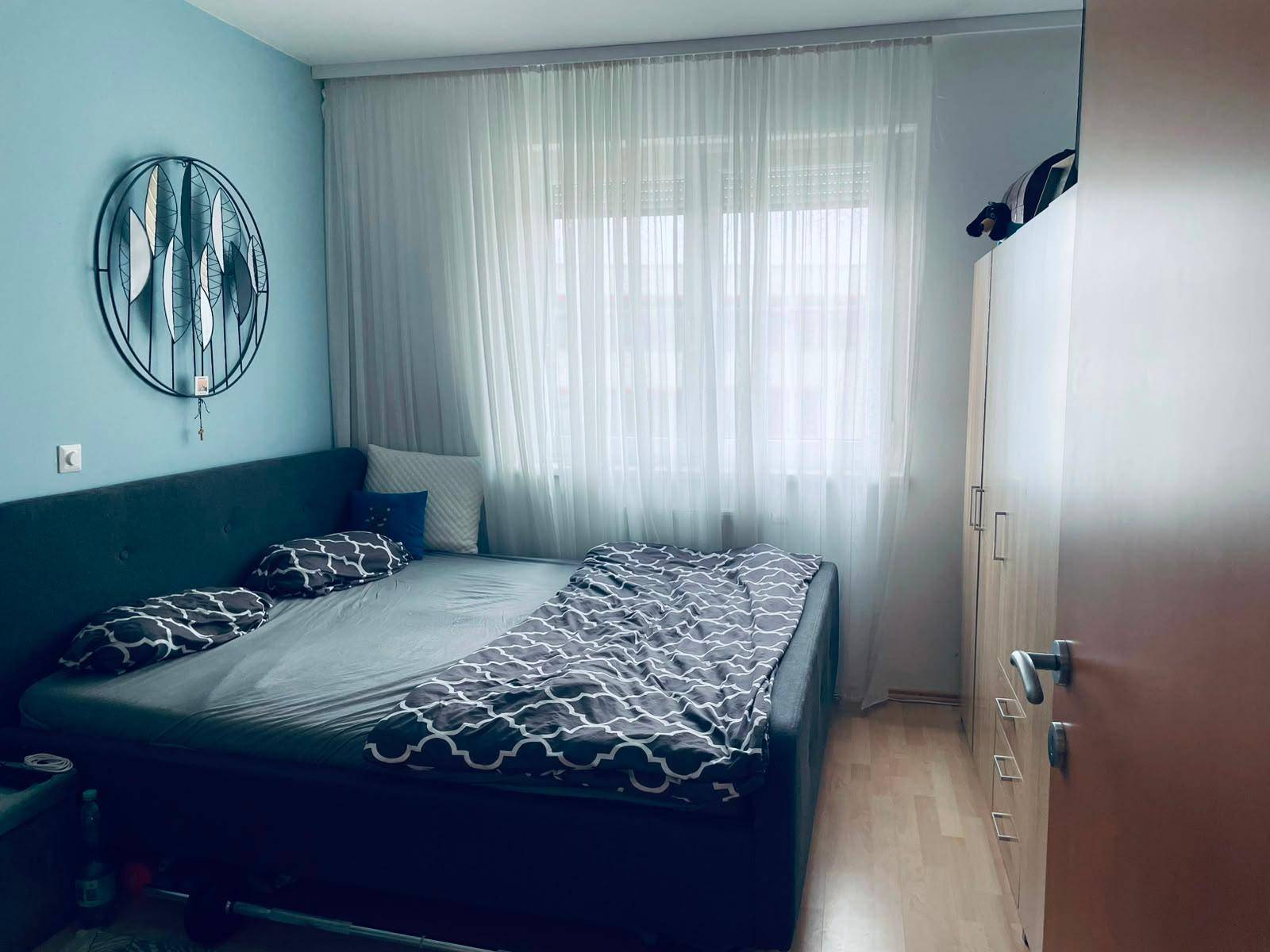 Gemütliches Schlafzimmer mit Doppelbett, Holzboden und hellblauen Wänden.
