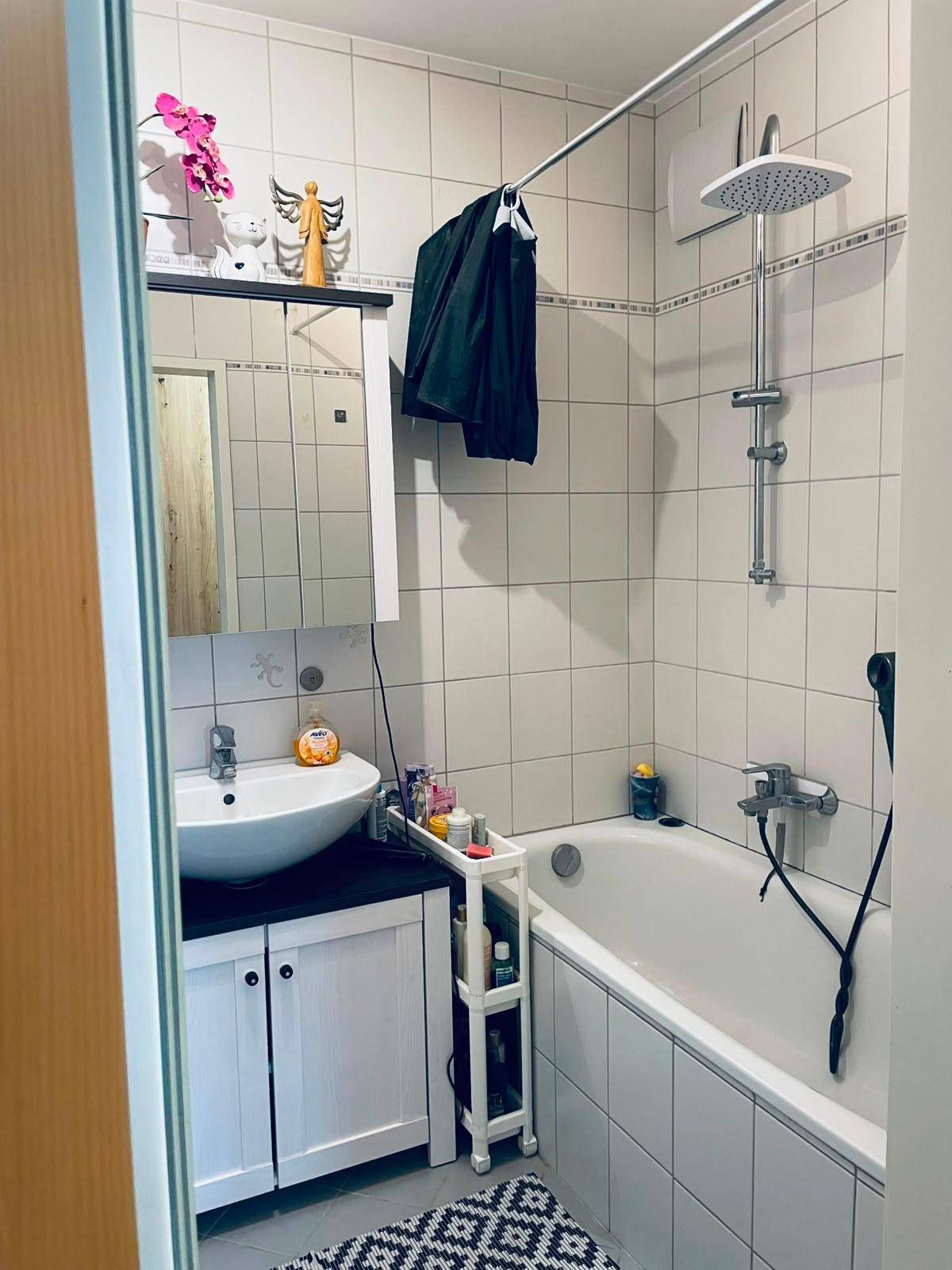Funktionales Badezimmer mit Badewanne, Duschfunktion und modernem Waschbecken.