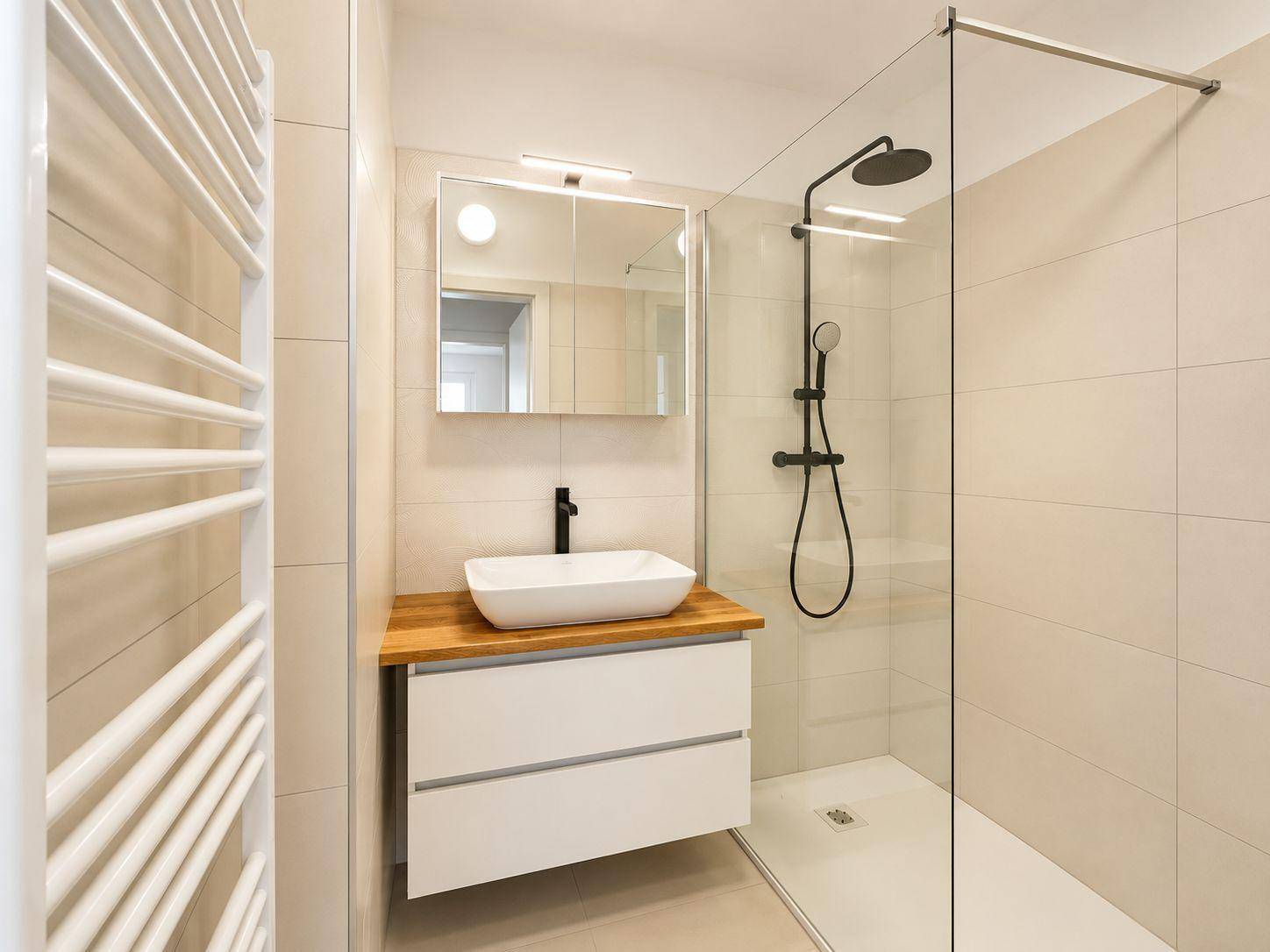Modernes Badezimmer mit begehbarer Dusche, Waschbecken und beheiztem Handtuchhalter.