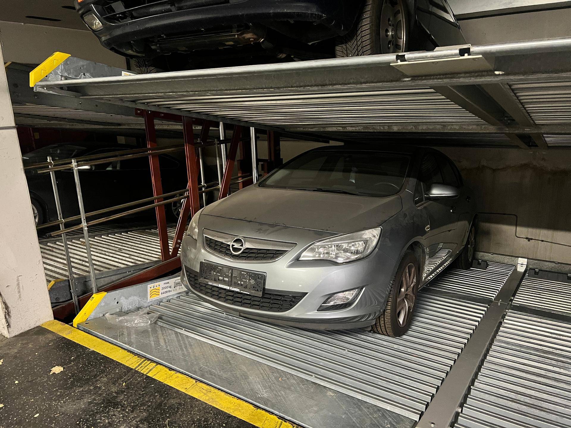 Tiefgarage mit mechanischem Doppelparker-System und zwei Fahrzeugen auf den Stellplätzen.