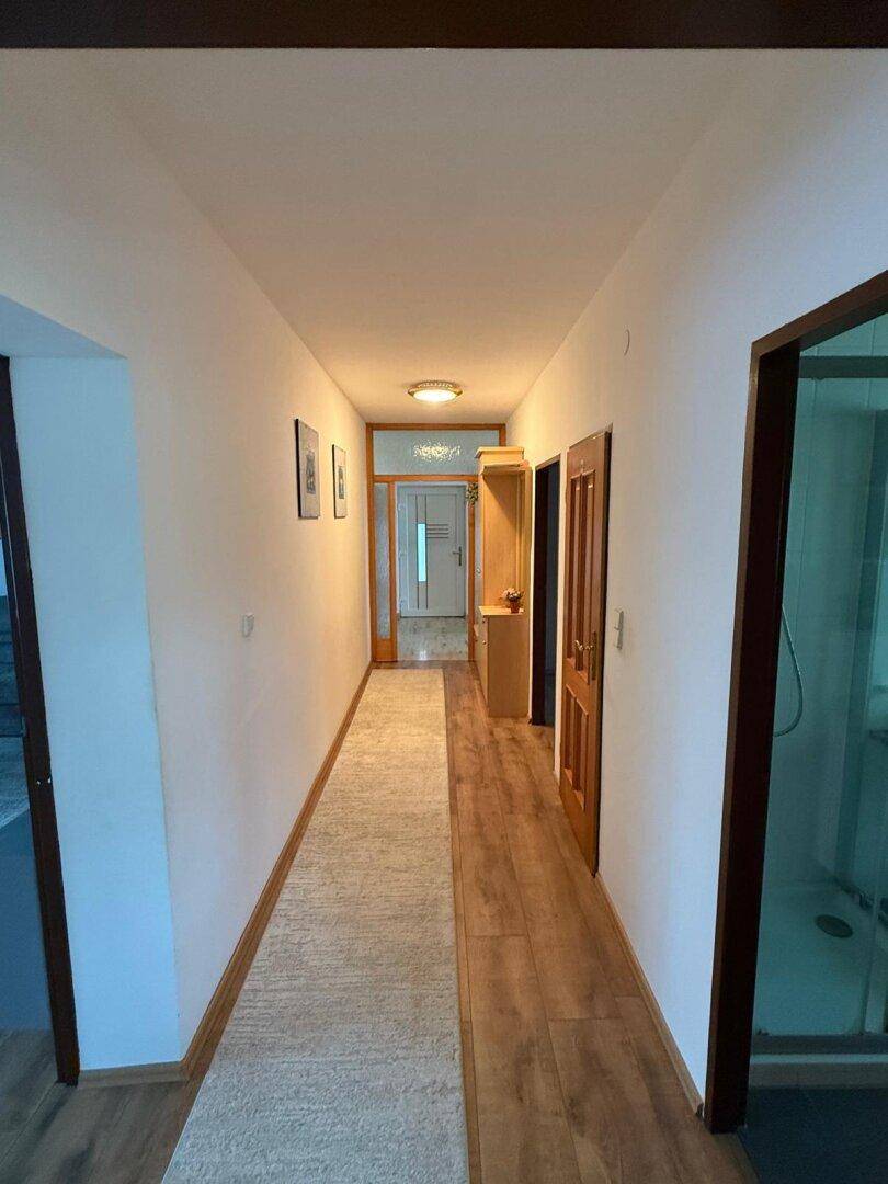 Langer Flur mit Laminatboden, Teppichläufer und Holztüren zu den angrenzenden Räumen.