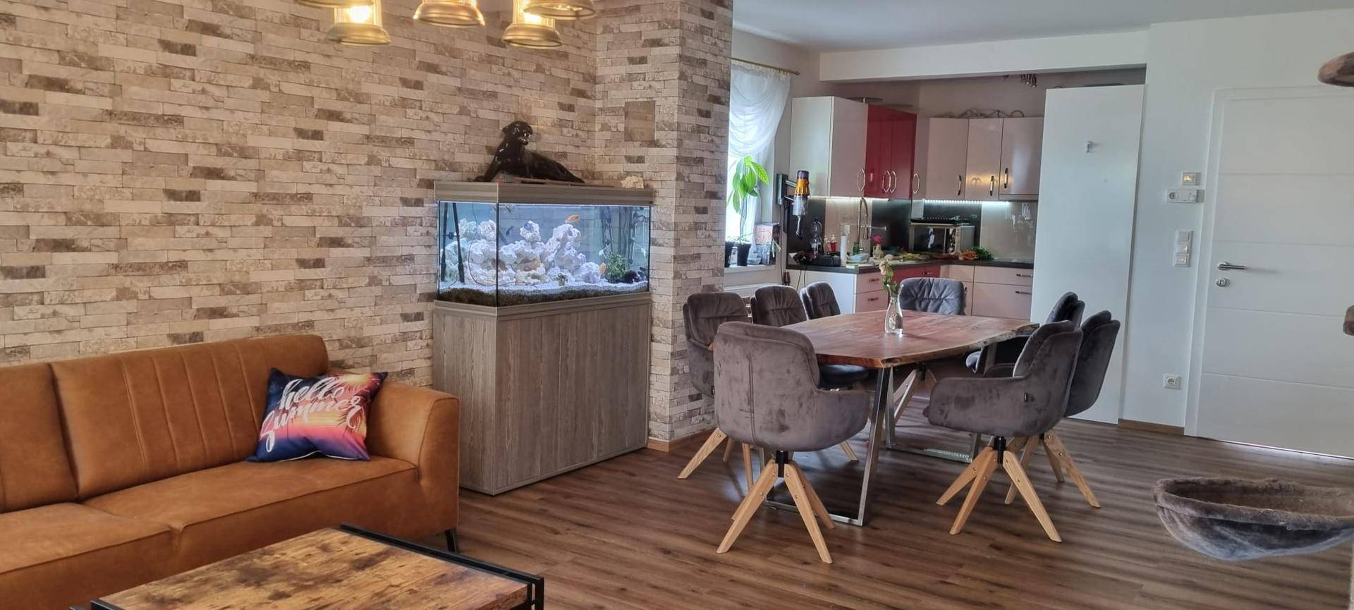 Heller Wohn-Essbereich mit Holztisch, bequemen Stühlen und Blick in die angrenzende Küche.