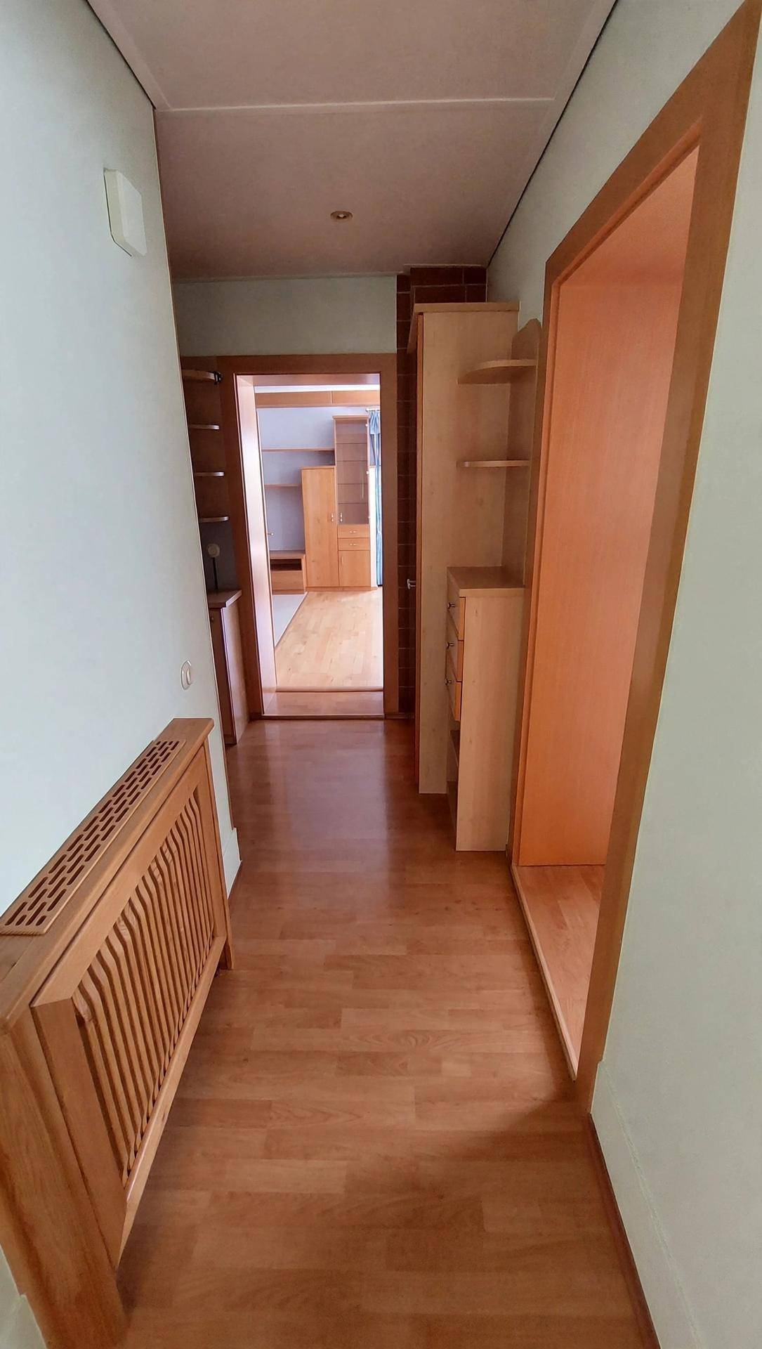 Heller Flur mit Holzfußboden und Holzverkleidung, der zu weiteren Räumen führt.