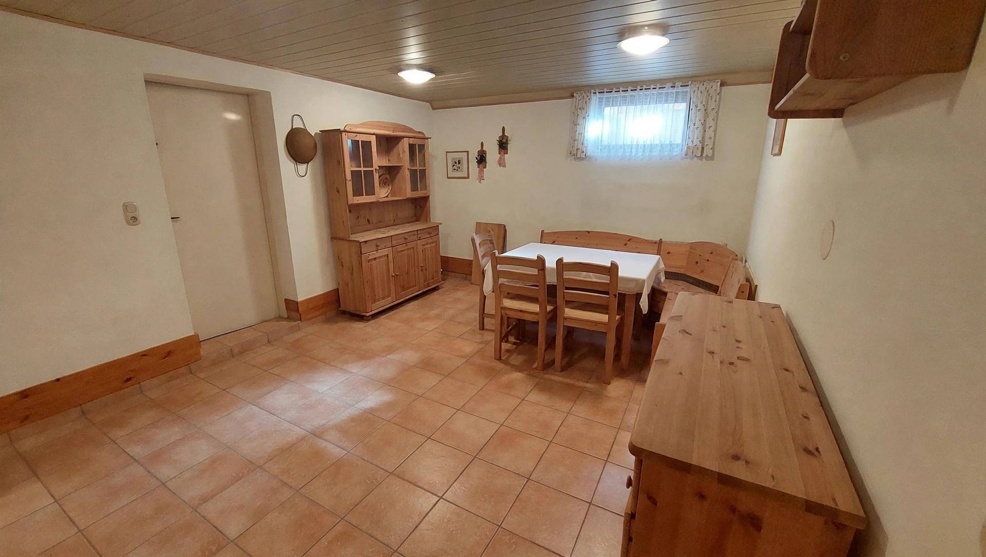 Gemütlicher Kellerraum mit Holzmöbeln, Esstisch und Terrakotta-Fliesenboden.