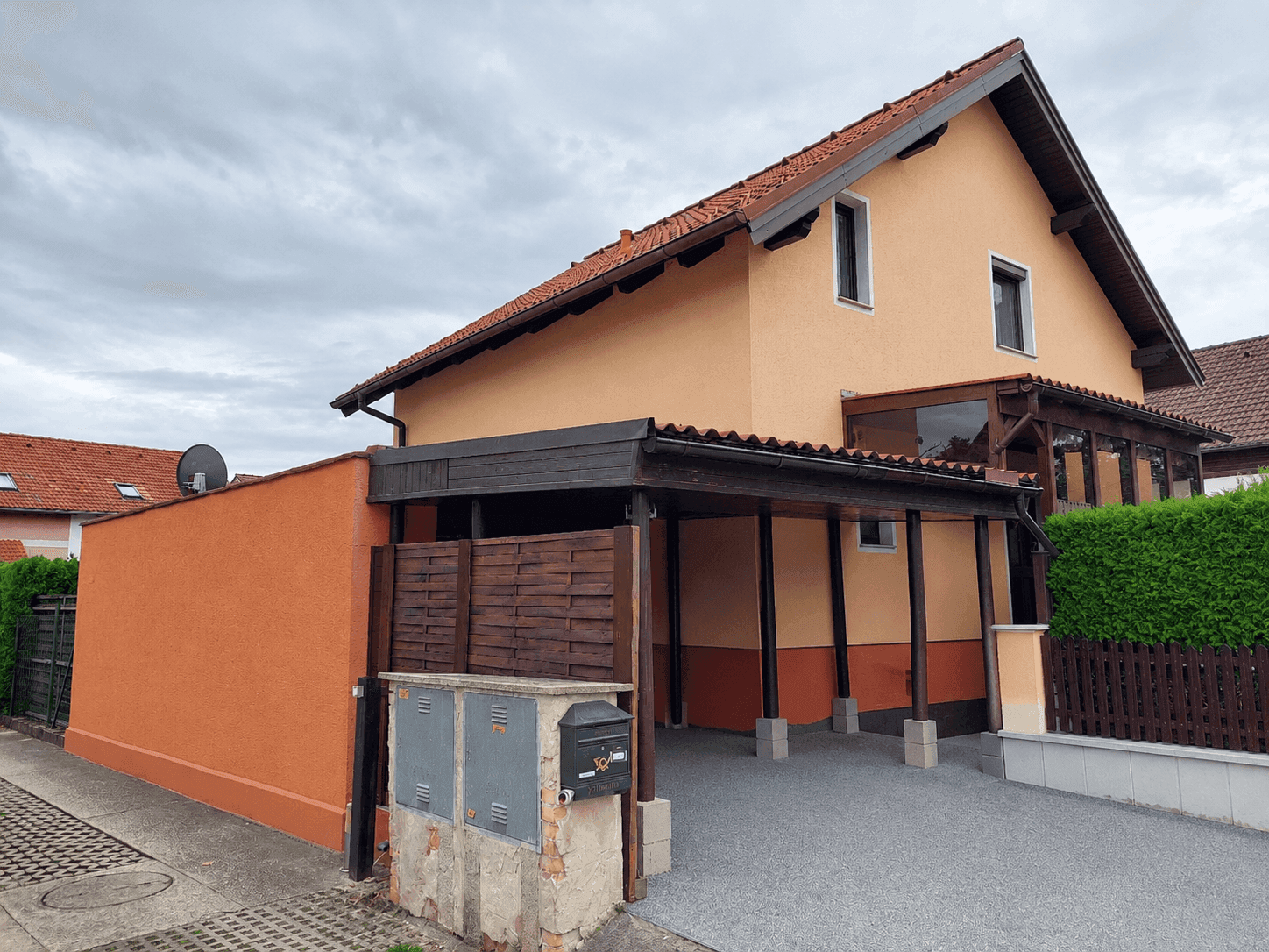 Seitenansicht des Hauses mit Carport, Garage und einem kleinen Vorgartenbereich.