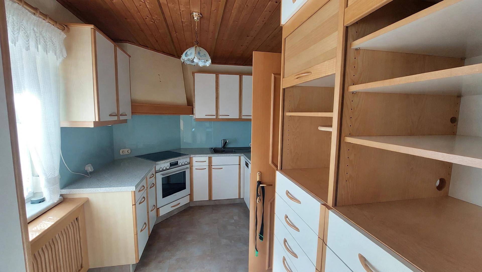 Funktionale Küche mit Holzdecke, weißen Schränken und integrierten Geräten.