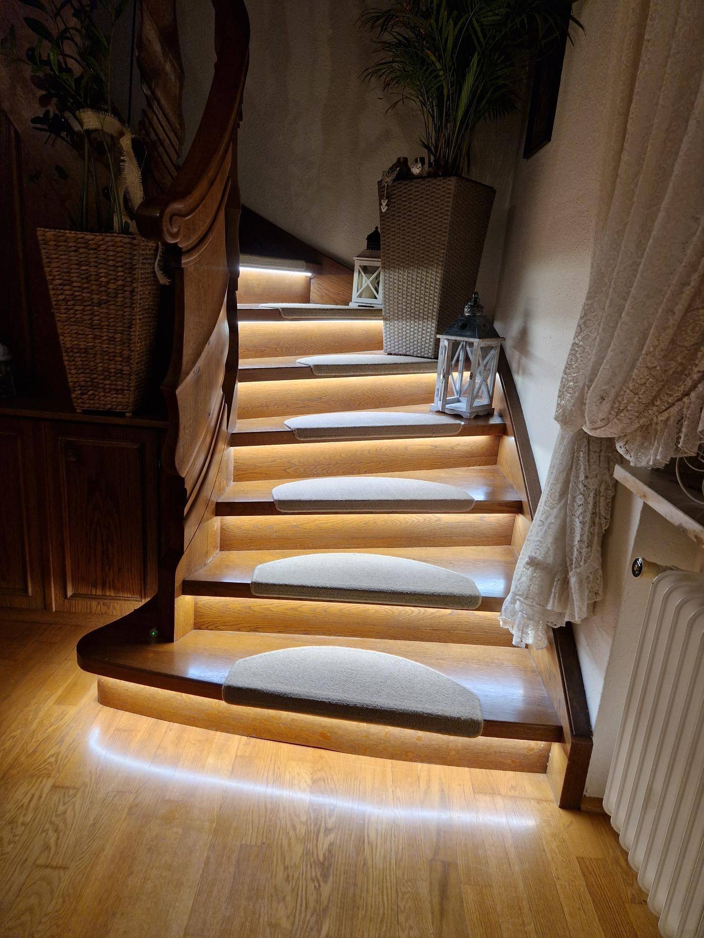 Elegante Holztreppe mit indirekter Beleuchtung und dekorativen Elementen.