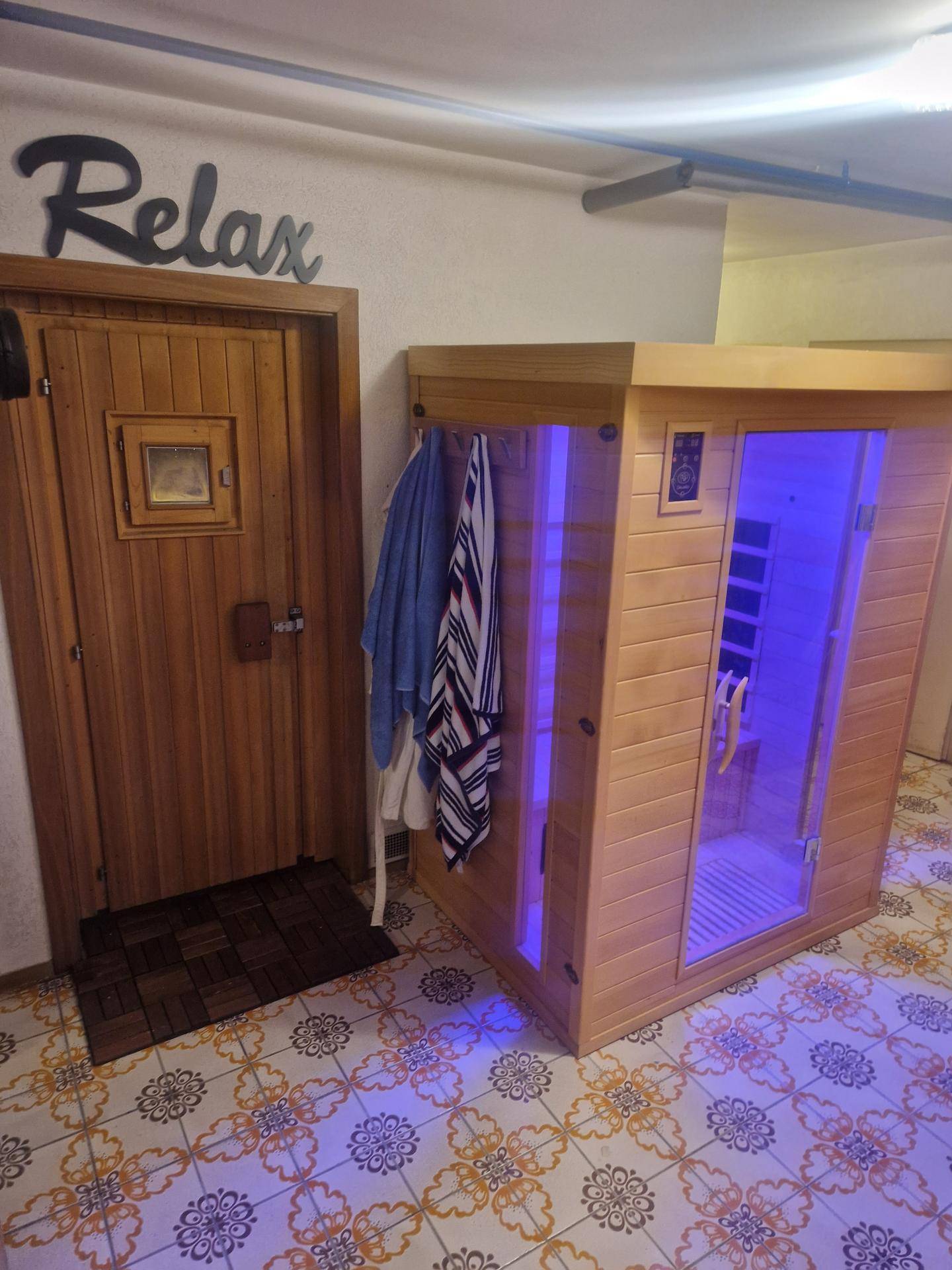 Wellnessbereich mit traditioneller Sauna und moderner Infrarotkabine auf gemustertem Fliesenboden.