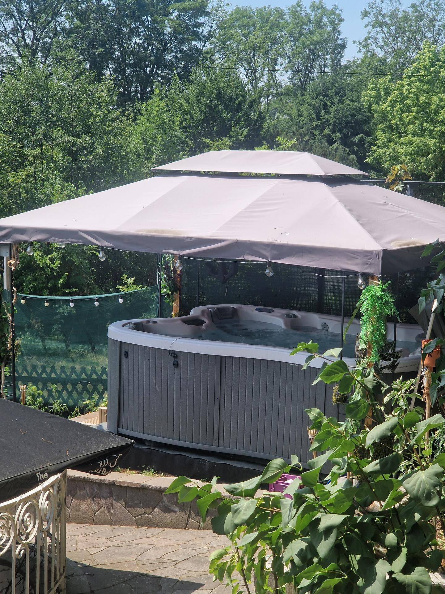 Whirlpool im Gartenbereich unter einem Pavillon, ideal für Entspannung im Freien.