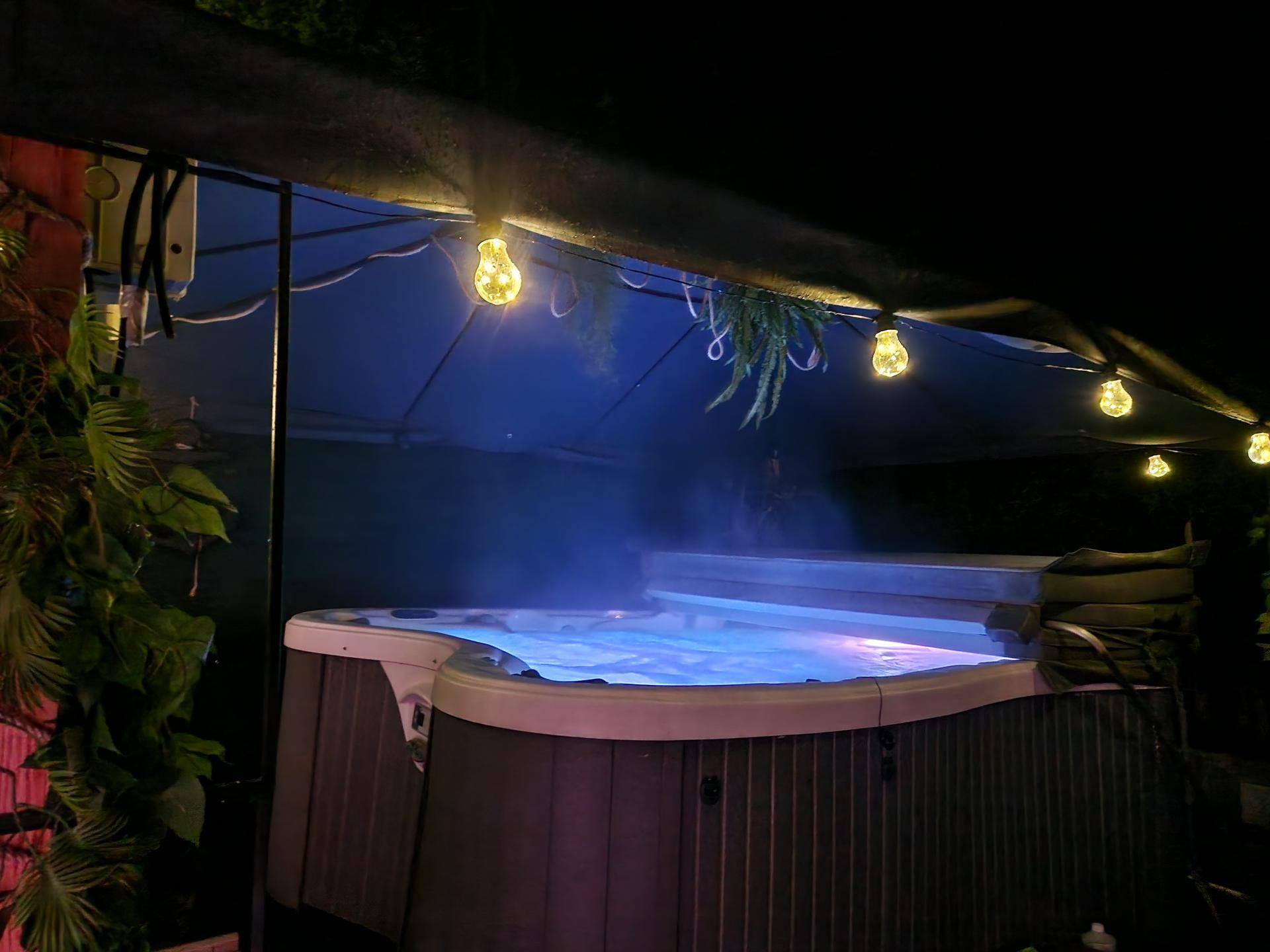 Beleuchteter Whirlpool im Freien bei Nacht, schafft eine entspannende Atmosphäre.
