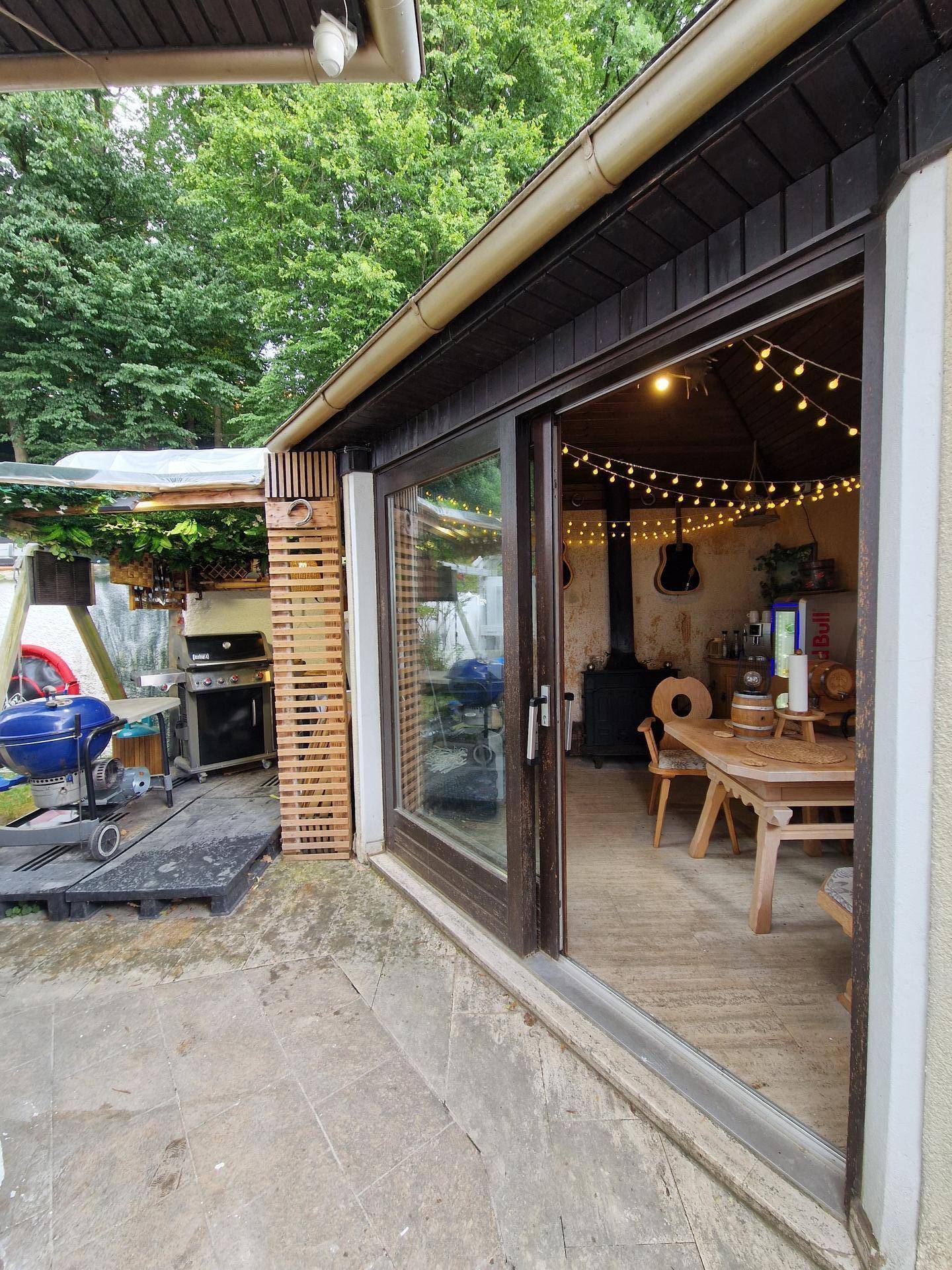 Gemütlicher Außenbereich mit Grillstation und Blick in einen rustikalen Essbereich.
