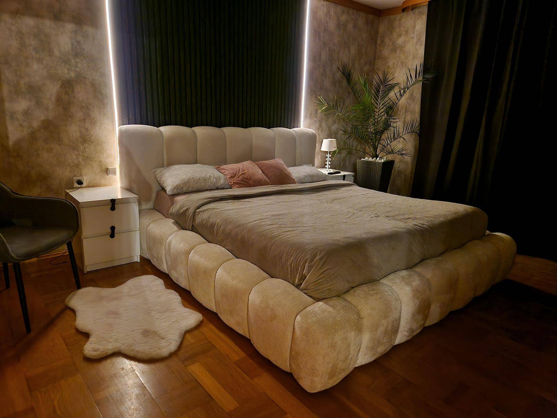 Modernes Schlafzimmer mit großem, gepolstertem Bett und indirekter Beleuchtung.