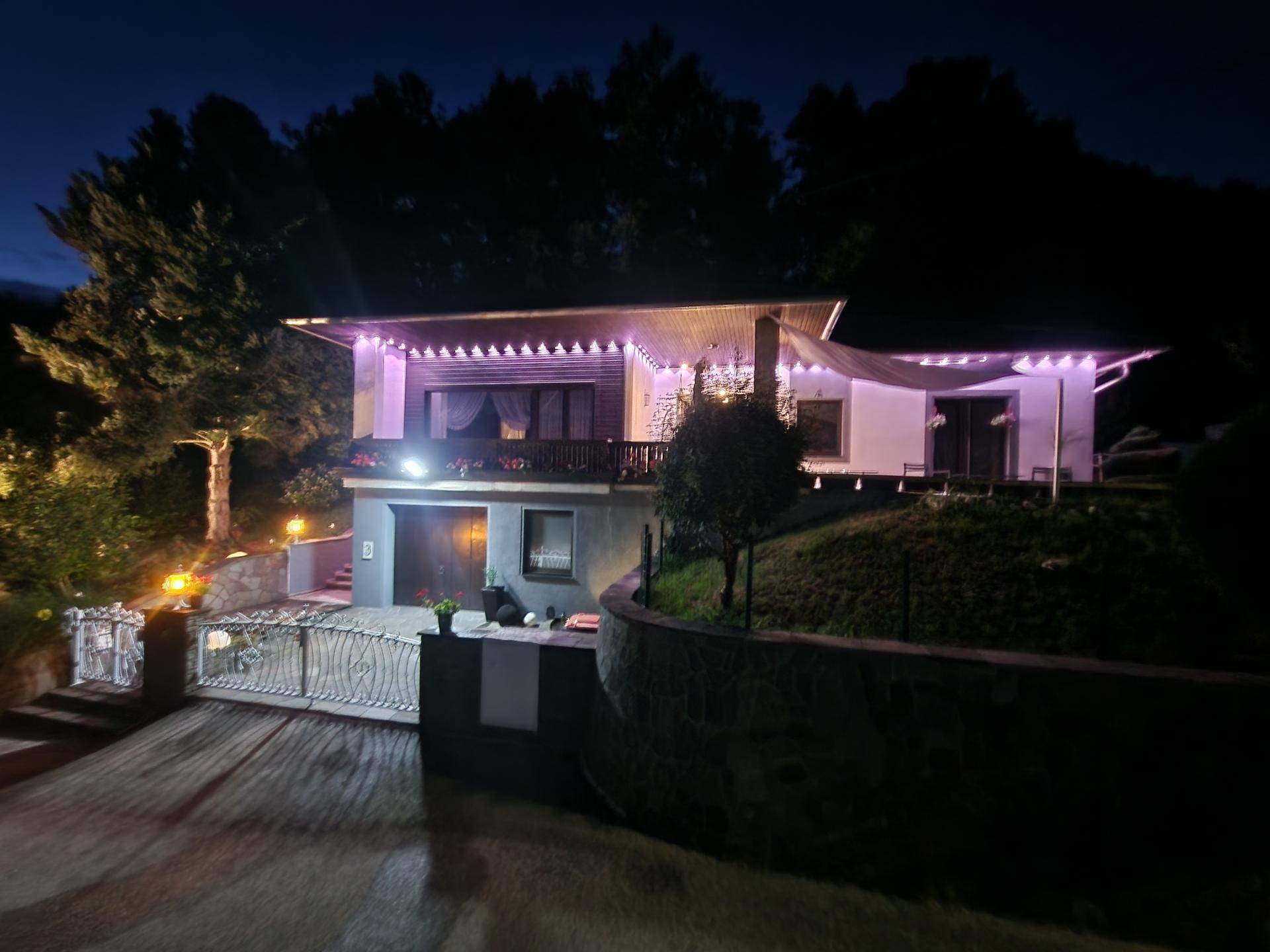Das Haus ist nachts beleuchtet und zeigt eine einladende Fassade mit Garten.