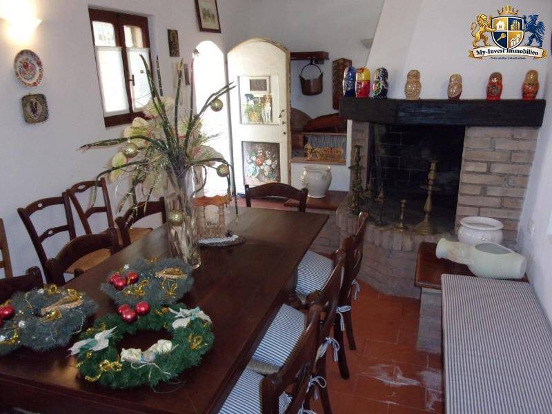 Rustikaler Essbereich mit großem Holztisch, traditionellen Stühlen und einem gemauerten Kamin für gemütliche Abende.