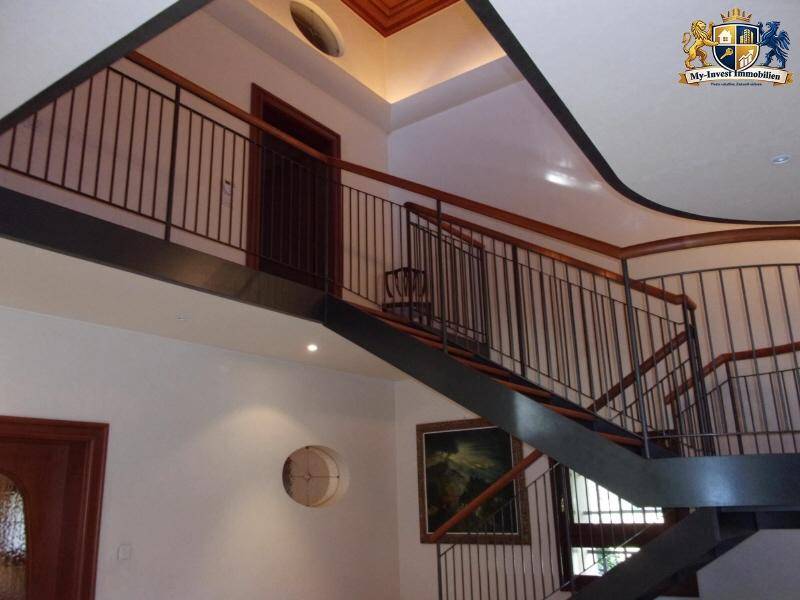Detailansicht der modernen Treppe mit Metallgeländer und Holzhandlauf in einem hellen Treppenhaus.