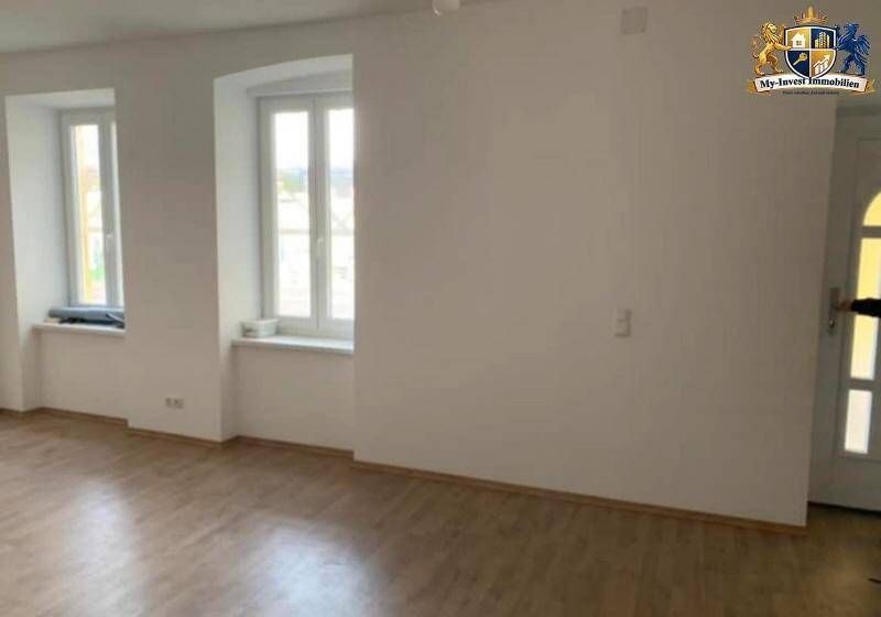Heller Wohnraum mit Laminatboden und hohen Fenstern, direkt neben dem Eingangsbereich gelegen.