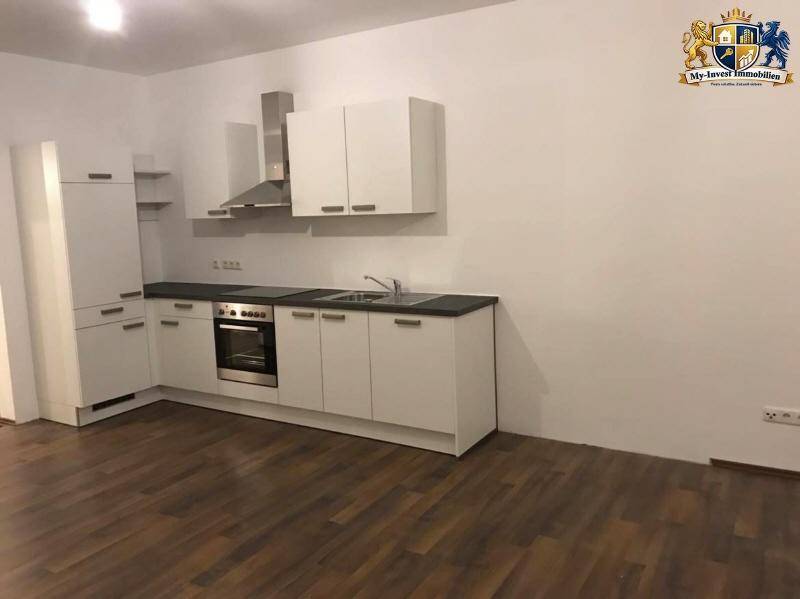 Moderne Einbauküche in Weiß mit Edelstahlofen und Dunstabzugshaube in einem neuen Raum.