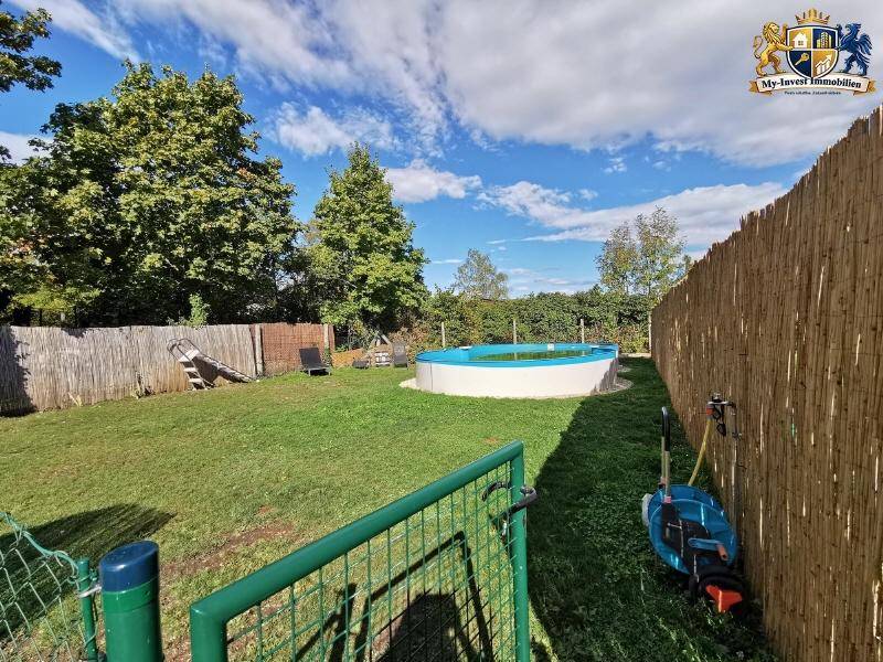 Großer Garten mit Rasenfläche, einem Aufstellpool und einer hohen Bambushecke als Sichtschutz.