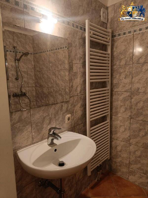 Badezimmer mit Fliesen, Waschbecken, Spiegel und Duschbereich.