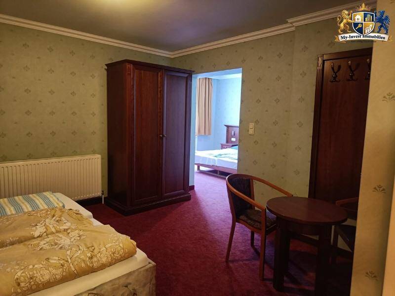 Geräumiges Schlafzimmer mit zwei Betten, Kleiderschrank und Zugang zu einem weiteren Raum.