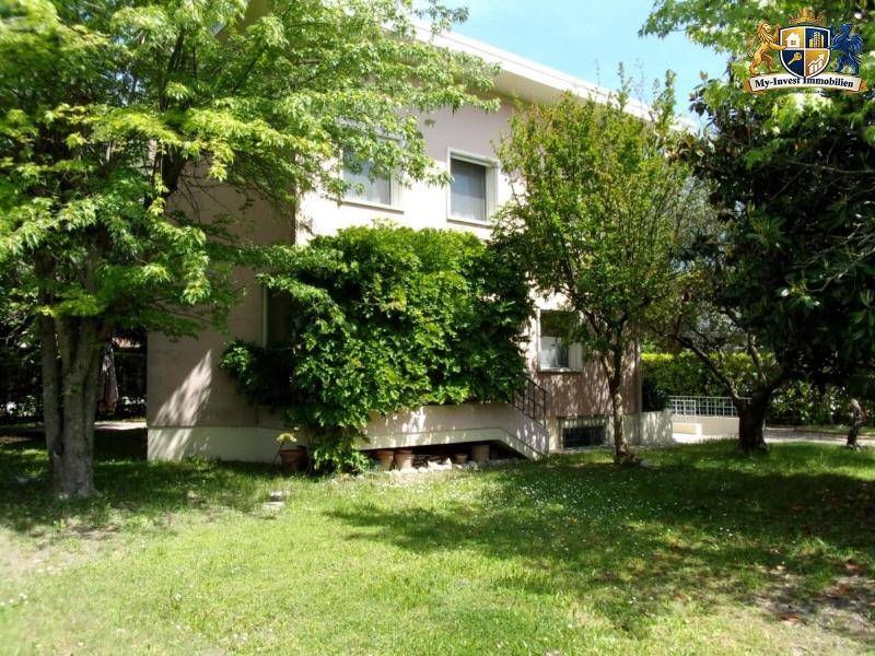 Seitliche Ansicht des Hauses mit üppiger Vegetation, Bäumen und einem weiteren Gartenbereich.