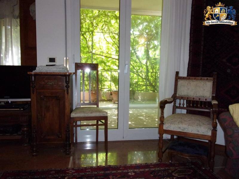 Wohnbereich mit großen Fenstertüren, die Zugang zu einem Balkon und viel natürliches Licht bieten.