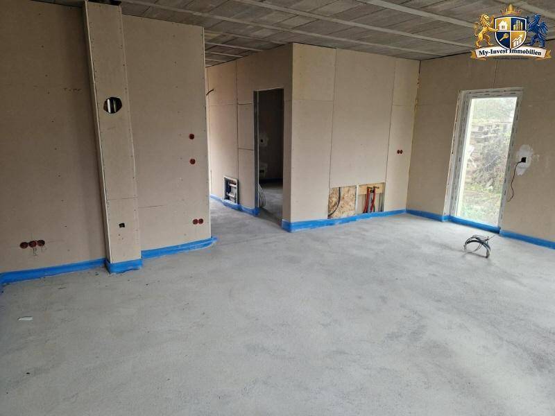 Innenansicht eines Hauses im Rohbau mit Trockenbauwänden und Betonboden, vorbereitet für den weiteren Ausbau.