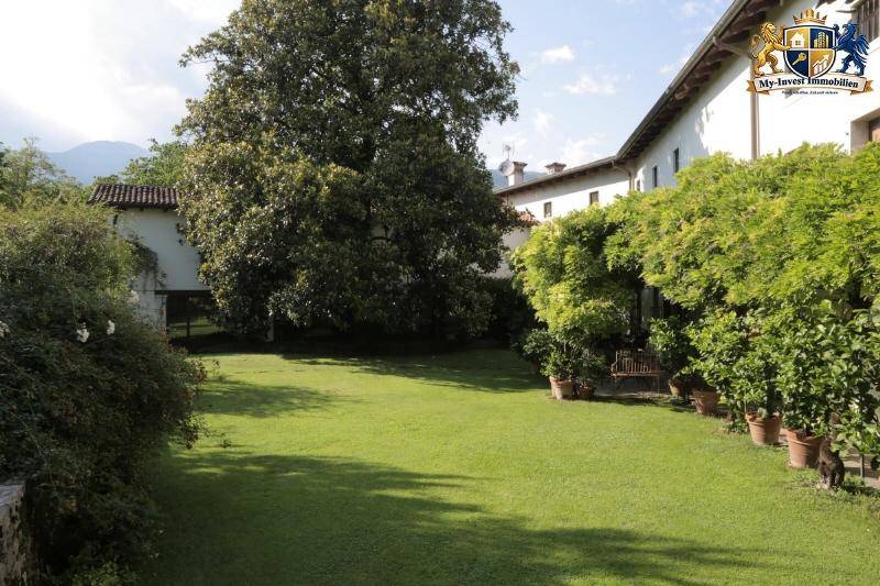 Großer, gepflegter Garten mit weitläufiger Rasenfläche und altem Baumbestand vor dem Haus.
