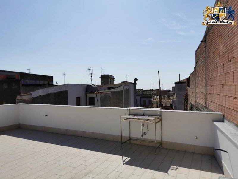 Funktionale Dachterrasse mit Außenwaschbecken und Blick auf die Dächer der Nachbargebäude.