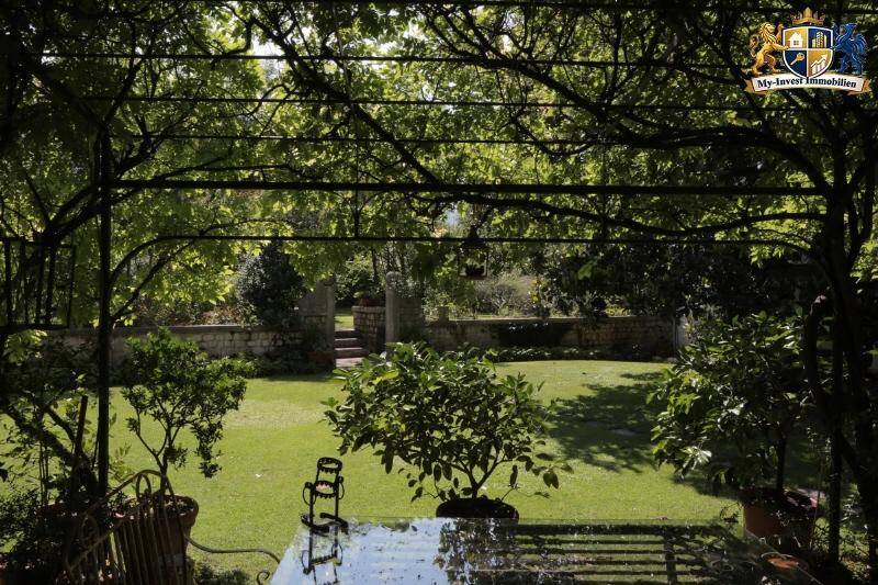 Idyllischer Essbereich im Freien unter einer grünen Pergola mit Blick auf den weitläufigen Garten.