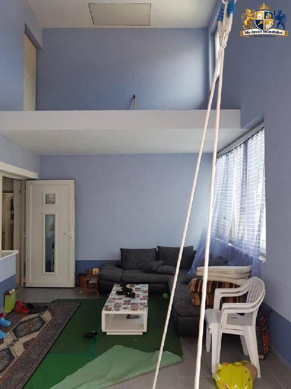 Wohnzimmer mit blauen Wänden, dunklem Ecksofa und einem offenen Bereich im oberen Stockwerk.