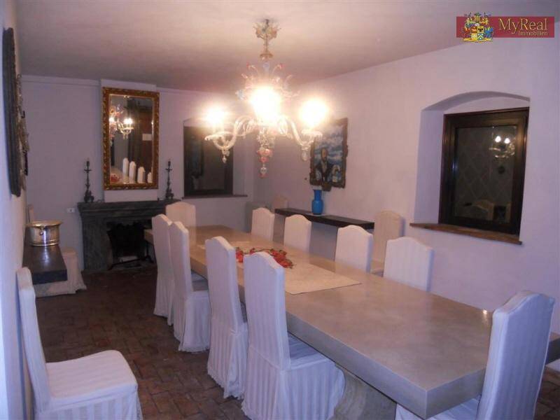 Elegantes Esszimmer mit langem Tisch, weißen Stühlen, Kamin und Kronleuchter in klassischem Stil.