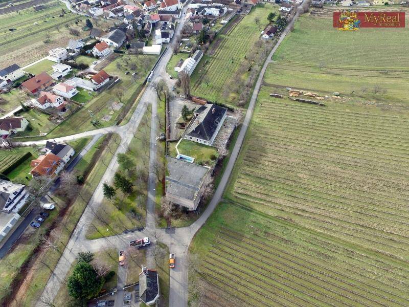 Luftaufnahme eines Anwesens mit mehreren Gebäuden, umgeben von Weinbergen und einer ländlichen Siedlung.