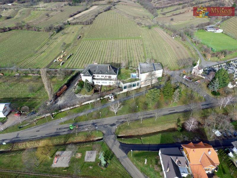 Weitläufige Luftaufnahme des Anwesens mit Weinbergen, Dorf und einem Spielplatz im Vordergrund.