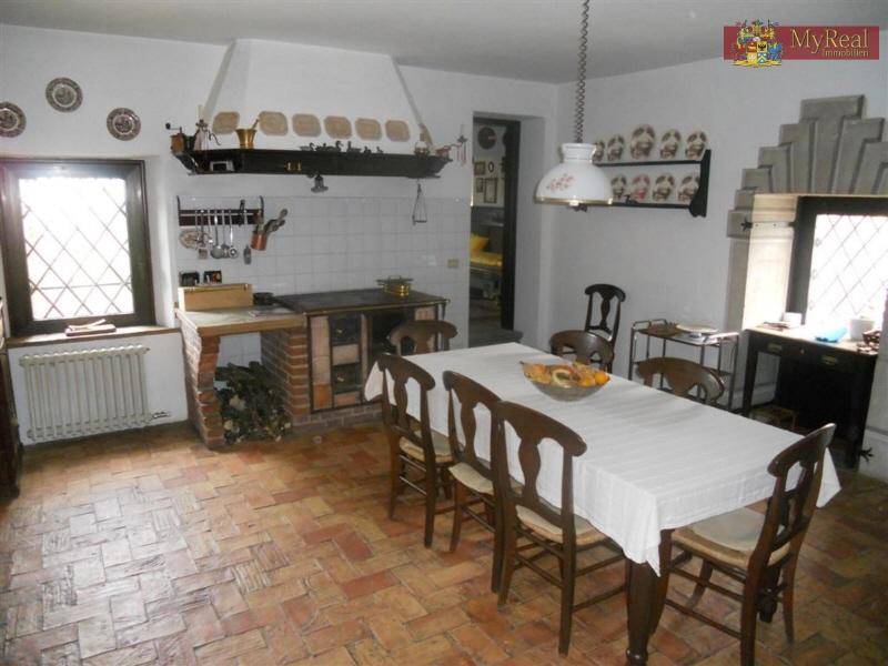 Rustikale Wohnküche mit großem Esstisch, traditionellem Herd und Terrakottaboden.