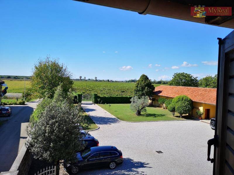 Weitläufiger Blick über Weinberge und grüne Felder von einem oberen Stockwerk.